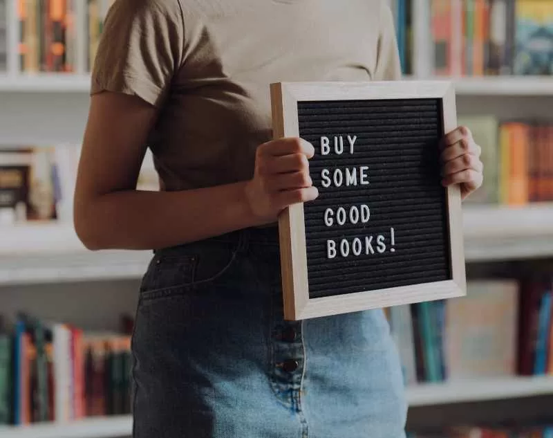 Woman with sign about leadership books for entrepreneurs